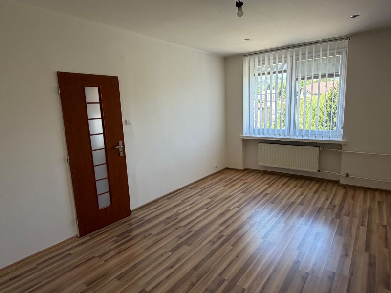 Egy szoba egy egyszobás lakásban, fa dekor padlóval és nagy ablakkal.