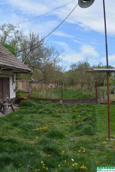 Családi ház Felsőszelibán gyepes udvarral és kerttel, körülötte kerítéssel.