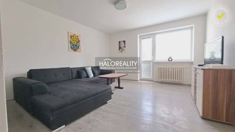 Nappali kanapéval és fa dekorációjú padlóval egy háromszobás lakásban.