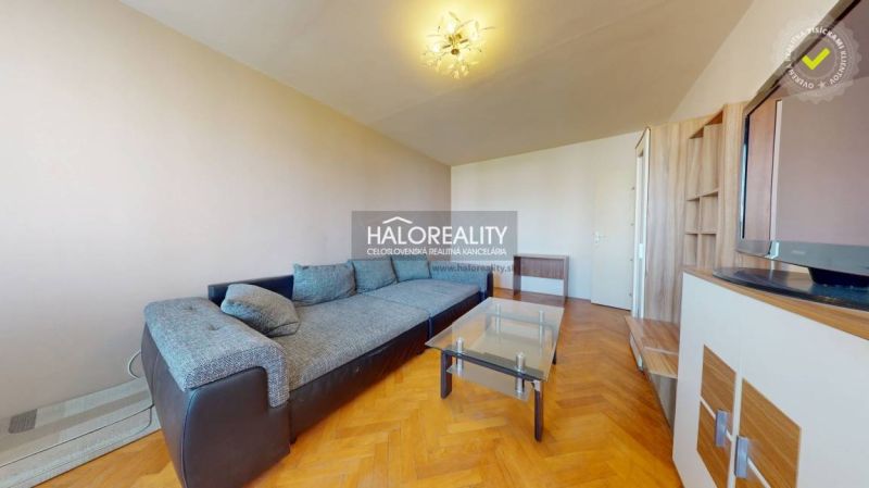 Nappali egy kétszobás lakásban kanapéval és fa dekorációjú padlóval.