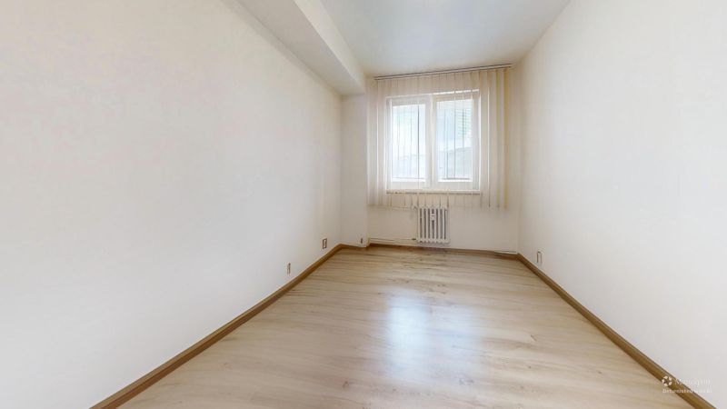 Világos szoba ablakkal és fa dekorációjú padlóval egy kétszobás lakásban.