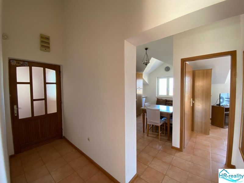Folyosó egy üdülő apartmanban kerámia padlóval, étkező sarok és szoba a háttérben.