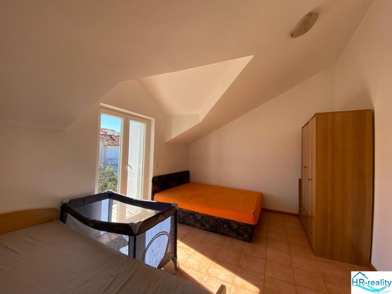 Nyaraló apartman hálószobája ágyakkal, szekrénnyel és gyerekággyal.