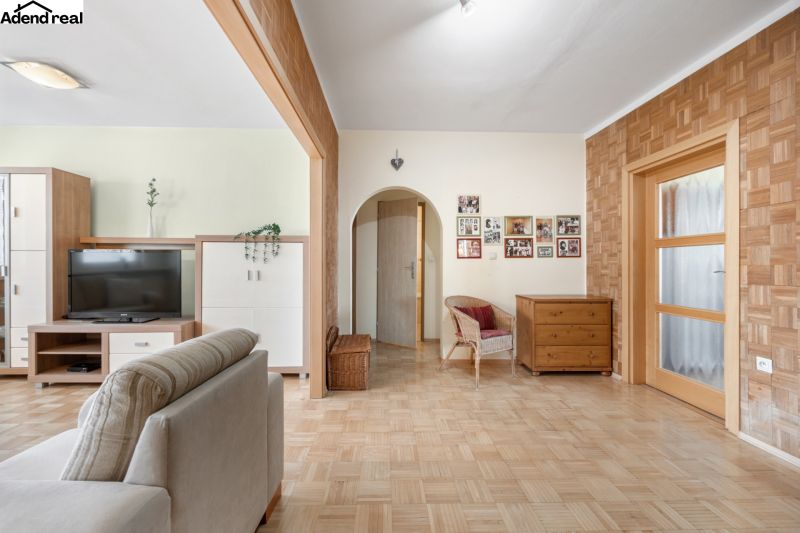 Nappali egy háromszobás lakásban, fa dekorációjú padlóval és bútorokkal.