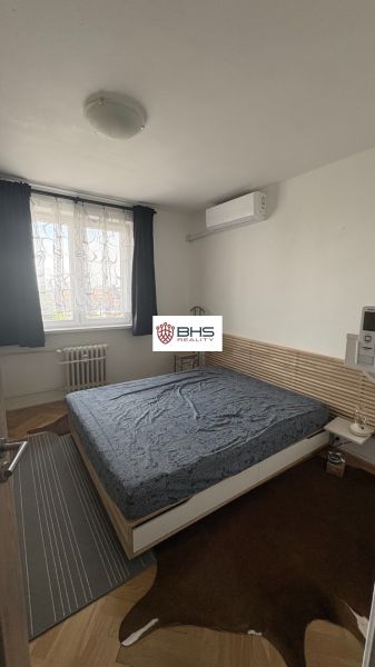 Hálószoba egy kétszobás lakásban, fa dekorációjú szőnyegekkel a padlón.