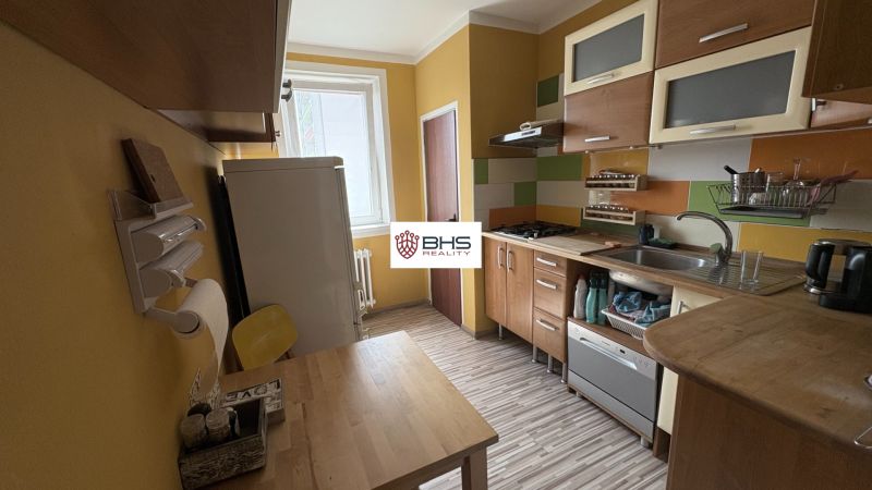 A kétszobás lakás konyhája, berendezett konyhabútor és fa dekorációjú padló.