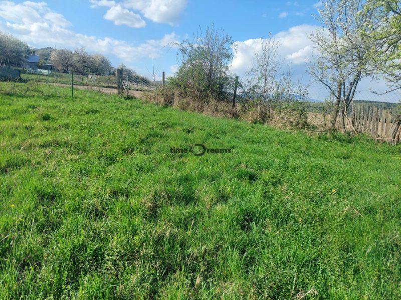 Lakóterületek Budiná faluban, zöld legelők és bekerített területek.