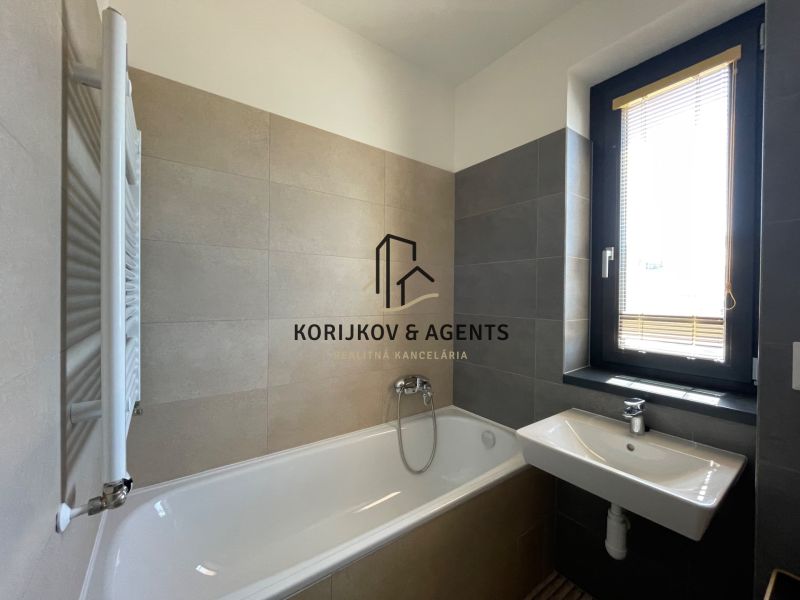 Fürdőszoba egy kétszobás lakásban káddal, mosdóval és ablakkal.
