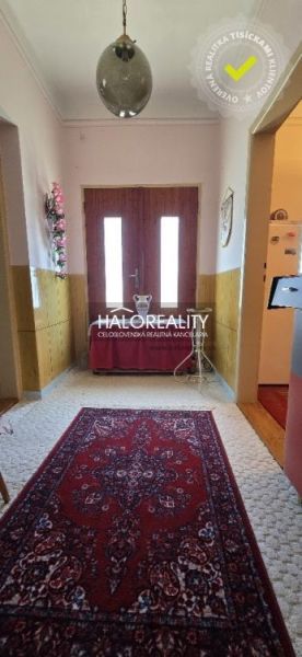 A családi ház folyosója szőnyeggel, faajtókkal és faldekorációkkal.