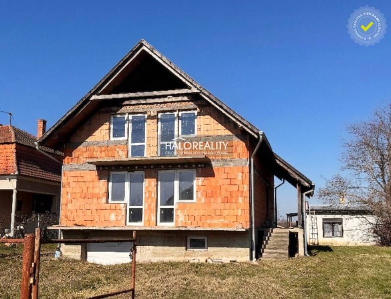 Családi ház Dunamocsban befejezetlen homlokzattal és nagy ablakokkal.