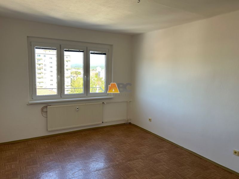 Kétszobás lakás szobája fa mintázatú padlóval és nagy ablakkal.