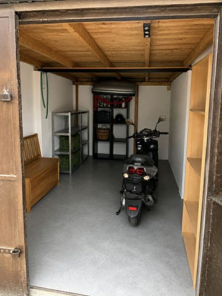 Garázs motorkával, fa mennyezettel és tároló polcokkal.