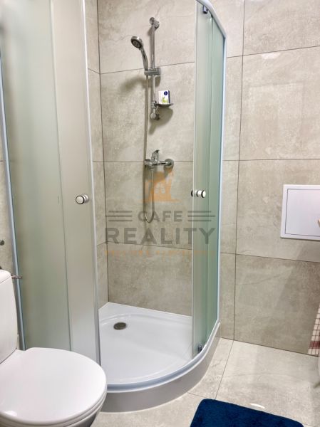 Zuhanykabin és WC az egyszobás lakás fürdőszobájában csempékkel.