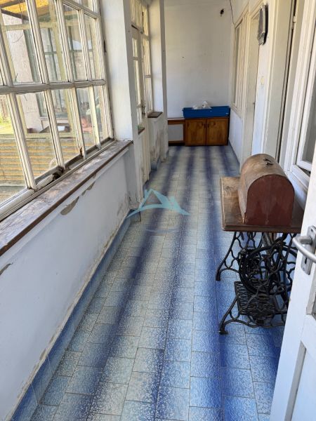 Egy családi ház folyosója kék csempékkel és nagy ablakokkal.
