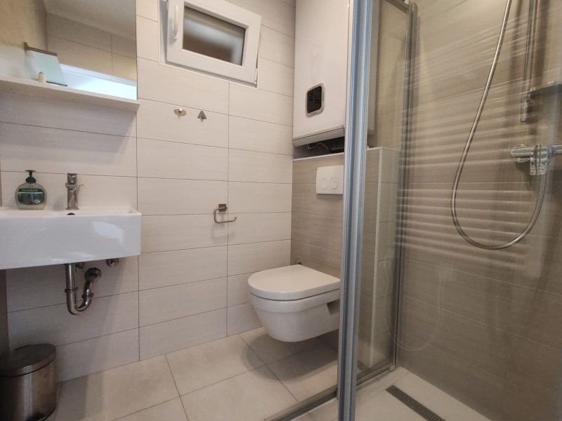 Fürdőszoba családi házban mosdóval, zuhanyzóval és függesztett WC-vel.