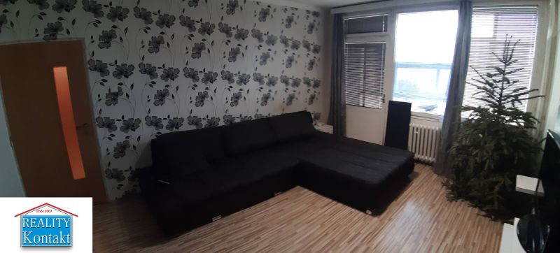 Nappali egy kétszobás lakásban virágos tapétával és fa mintázatú padlóval.
