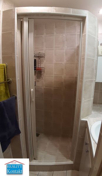 Zuhanyzó a fürdőszobában csempével egy kétszobás lakásban.