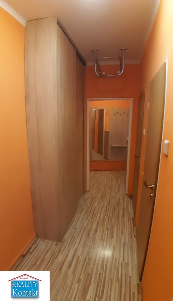 Narancssárga falú és fa dekorációjú padlójú folyosó egy kétszobás lakásban.