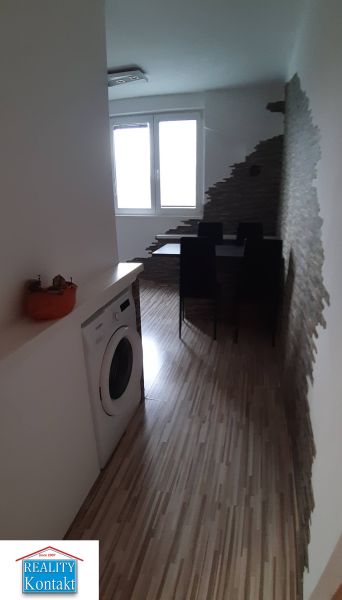 Étkező sarok fa mintás padlóval, mosógéppel és érdekes fallal egy kétszobás lakásban.