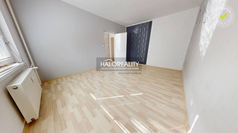 Egy szoba egy egyszobás lakásban fa dekorációjú padlóval és szürke falakkal.