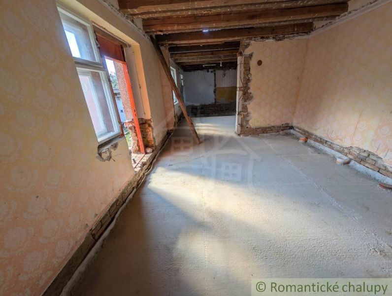 Családi ház belső tere látszó fa mennyezettel és sérült falakkal.