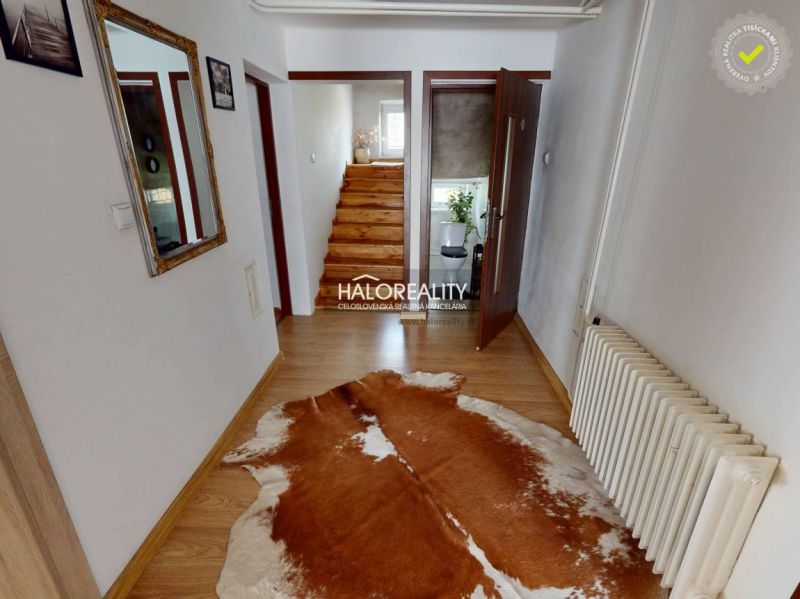 Családi ház belső tere fa dekorációjú padlóval és korláttal ellátott lépcsővel.