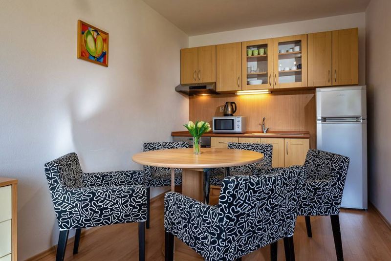 Konyhasarok étkezőasztallal és székekkel a nyaraló apartmanban, fa dekorációjú padlóval.
