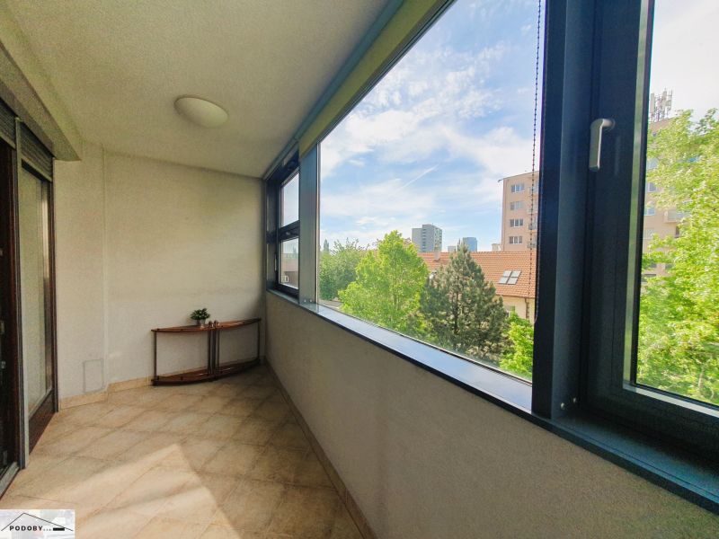 Üvegezett loggia egy 3 szobás lakásban, kilátással a zöldövezetre és a városi panorámára.