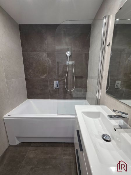 Fürdőszoba egy háromszobás lakásban káddal, zuhanyfallal és modern mosdóval.