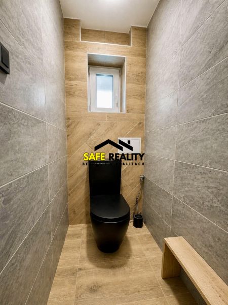 WC egy családi házban fekete WC-vel és fa dekorációjú padlóval.