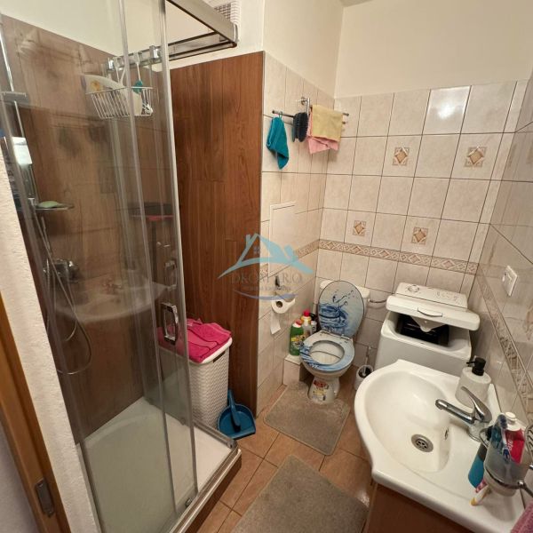Fürdőszoba zuhanyzóval és csempével egy egyszobás lakásban.