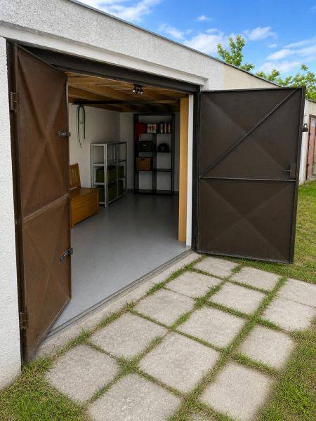 Nyitott garázs a Gúgska utcán Érsekújváron, polcokkal és egyenes gyepfelülettel.