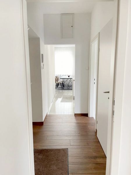 A háromszobás lakás folyosója fa dekorációjú padlóval az étkezőbe vezet.