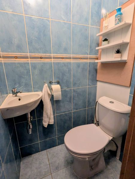 Fürdőszoba kék csempékkel és WC-vel egy kétszobás lakásban, polcok a falon.