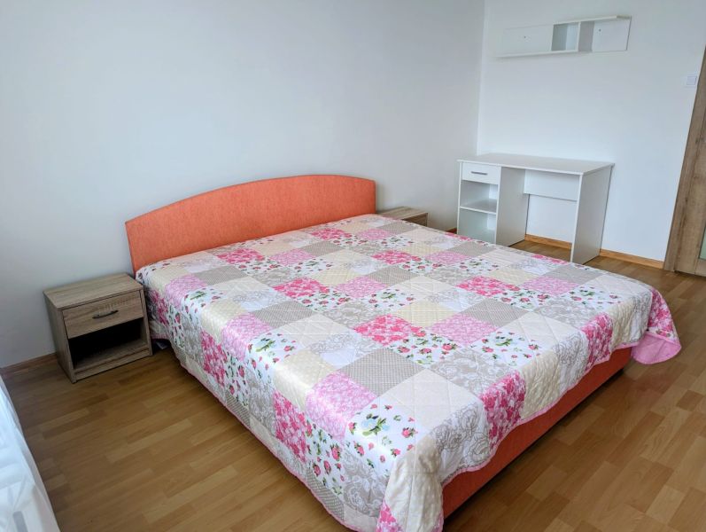 Hálószoba egy kétszobás lakásban ággyal, íróasztallal és fa dekorációjú padlóval.
