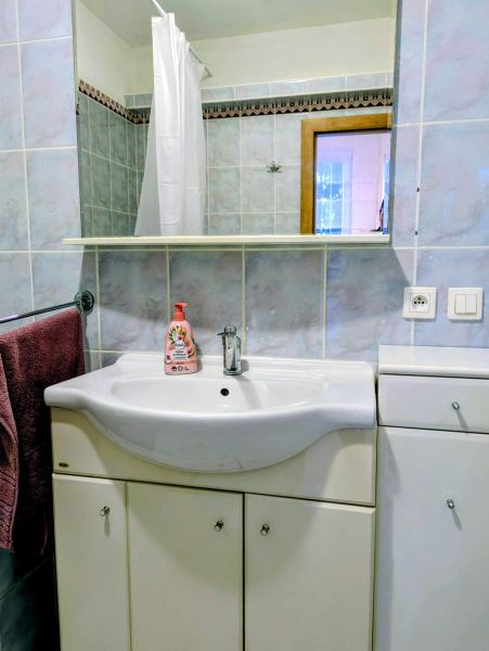 Fürdőszoba egy kétszobás lakásban mosdóval, tükörrel és kék csempékkel.