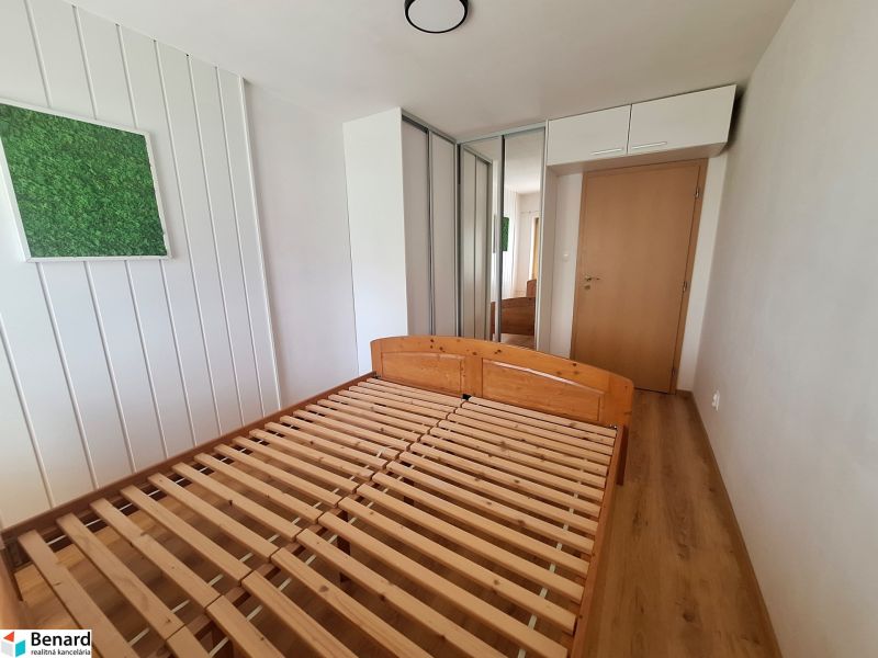 Hálószoba egy kétszobás lakásban, fa ággyal, beépített szekrénnyel és faldekorációval.