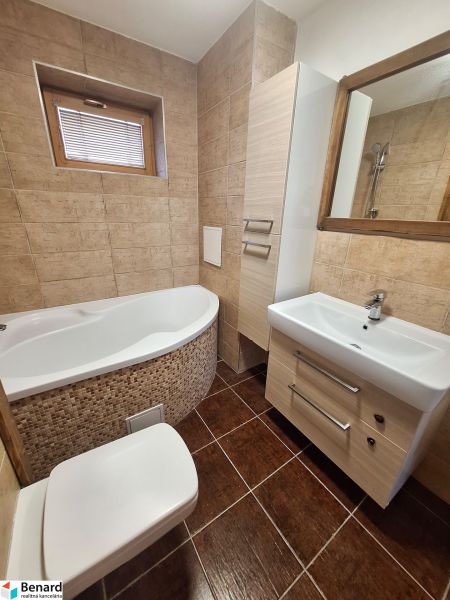 Fürdőszoba sarokkáddal, mosdóval és WC-vel egy kétszobás lakásban.