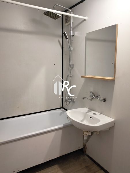 Fürdőszoba egy háromszobás lakásban, káddal és mosdóval ellátott zuhanyfejjel.