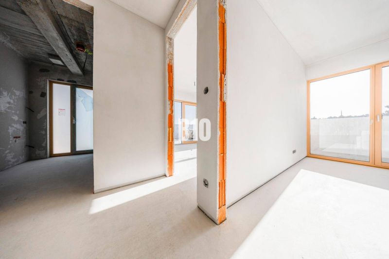 3 szobás lakás belső tere nagy ablakokkal és beton mennyezettel.