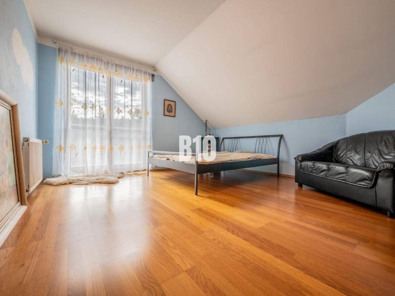 Hálószoba családi házban ággyal, bőrkanapéval és fa padlóval.