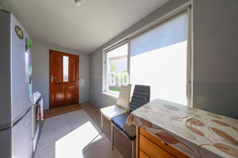 Családi ház konyhája napos ablakokkal és faasztallal.