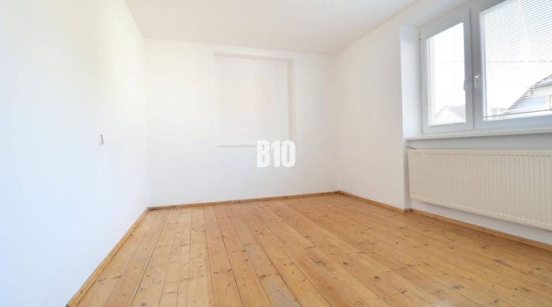 Világos szoba fa mintázatú padlóval és nagy ablakkal egy családi házban.
