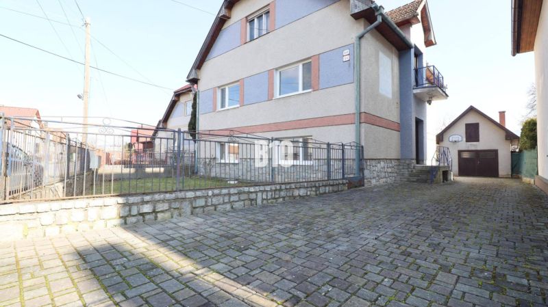 Családi ház Turánban kőkerítéssel és kövezett udvarral.