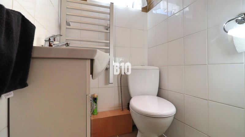 Fürdőszoba egy családi házban fehér csempékkel, mosdóval és WC-vel.