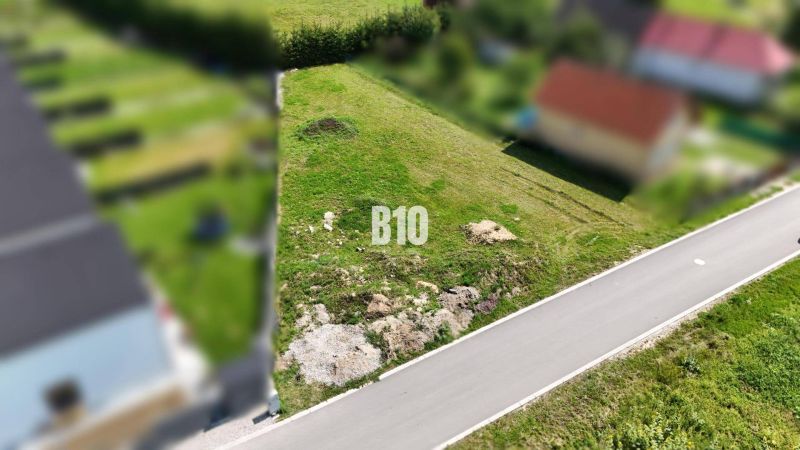 Lakóterületek Diakovában, zöld terület az aszfaltút mellett.
