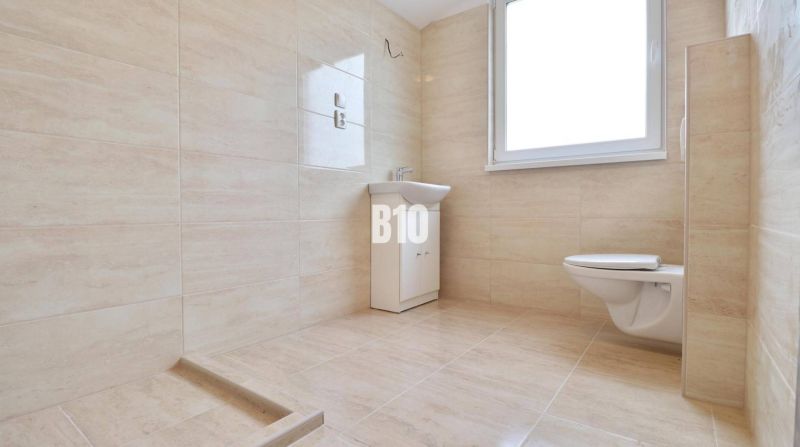 Fürdőszoba mosdóval és WC-vel egy családi házban csempézett burkolattal.