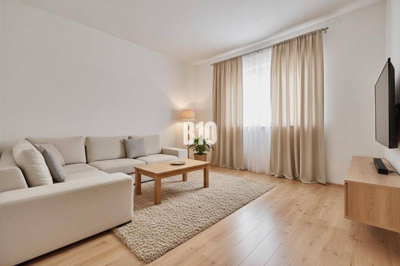 Családi ház nappalija bézs kanapéval, asztallal és fa dekorációjú padlóval.