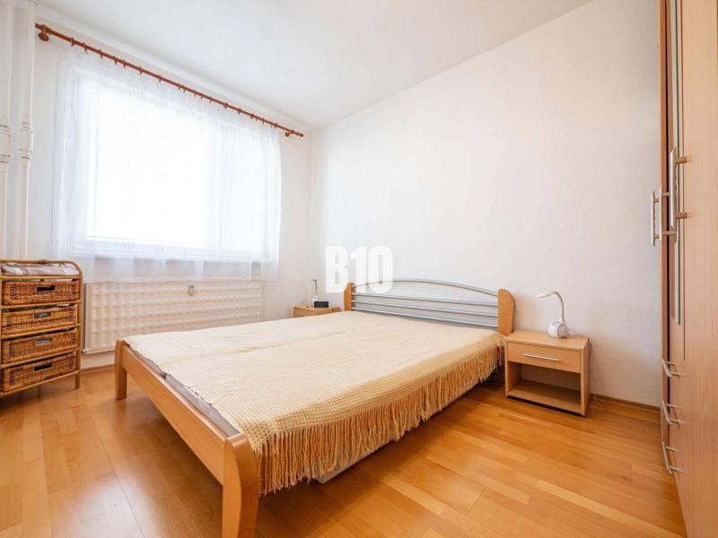 Hálószoba egy kétszobás lakásban, ággyal és fa dekorációjú padlóval.