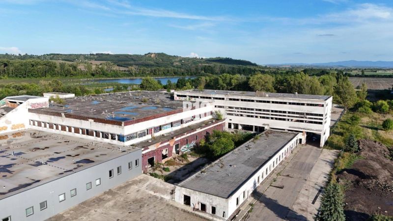 Gyártóhelyiségek Lévában elhagyatott épületekkel, amelyeket természet és vízfelület vesz körül.